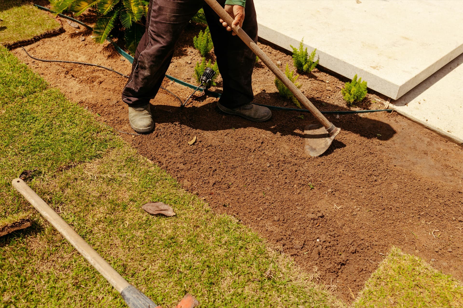 Worker leveling soil after property restoration work
